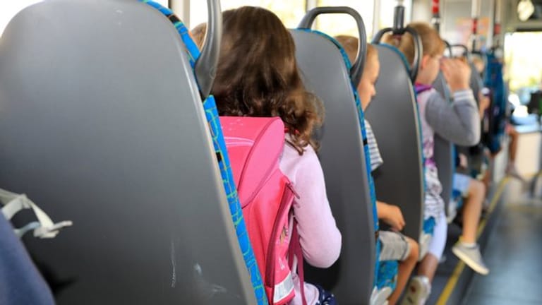 Kinder sitzen mit ihrem Ranzen in einem Schulbus (Symbolbild): Bei einem Unfall wurden 17 Grundschüler verletzt.