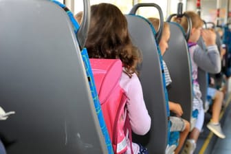 Kinder sitzen mit ihrem Ranzen in einem Schulbus (Symbolbild): Die Polizei ermittelt gegen einen Busfahrer.