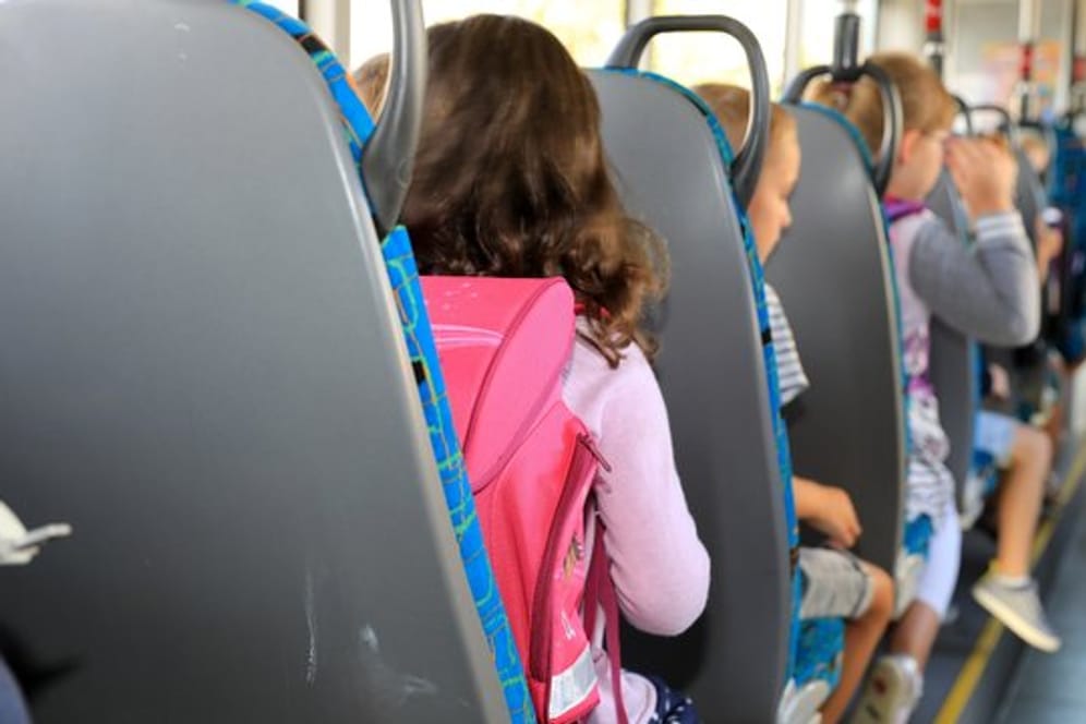 Kinder sitzen mit ihrem Ranzen in einem Schulbus (Symbolbild): Die Polizei ermittelt gegen einen Busfahrer.