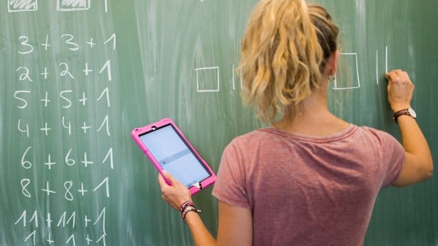 Eine Lehrerin mit Kreide und Tablet im Mathematikunterricht einer 8.