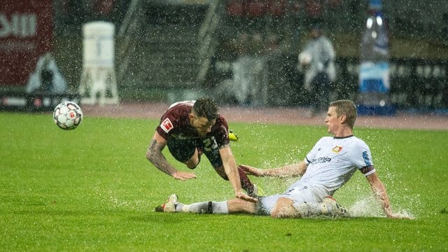 Der Leverkusener Lars Bender (r) grätscht gegen den Nürnberger Tim Leibold.