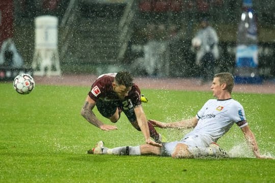 Der Leverkusener Lars Bender (r) grätscht gegen den Nürnberger Tim Leibold.