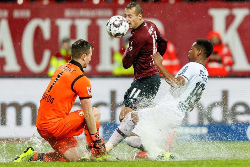 Wasserschlacht: Leverkusens Torwart Lukas Hradecky rettet kurz vor Schluss gegen Nürnbergs Adam Zrelak (M.), Verteidiger Wendell kommt zu spät.