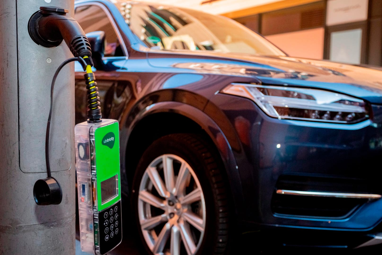 Ein Auto lädt an einer Ladesäule, die sich in einer Straßenlaterne befindet: Die Umstellung auf Elektroautos wird massive Auswirkungen auf die Wirtschaft haben.