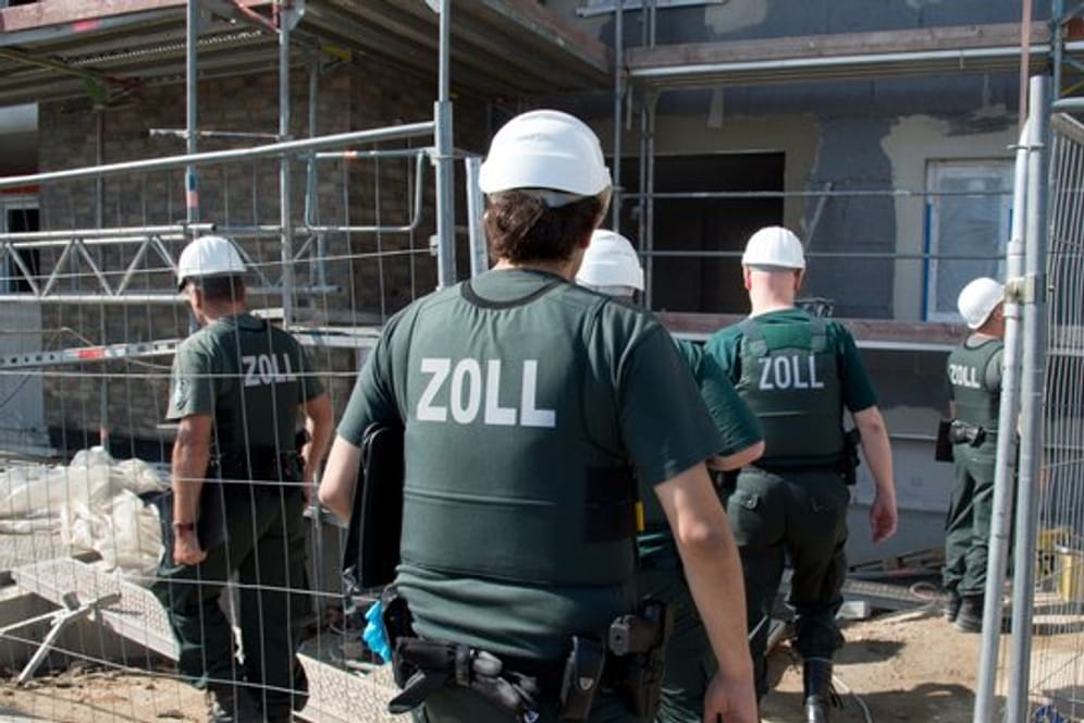 Zollbeamte betreten bei einer Razzia gegen Schwarzarbeit eine Baustelle.