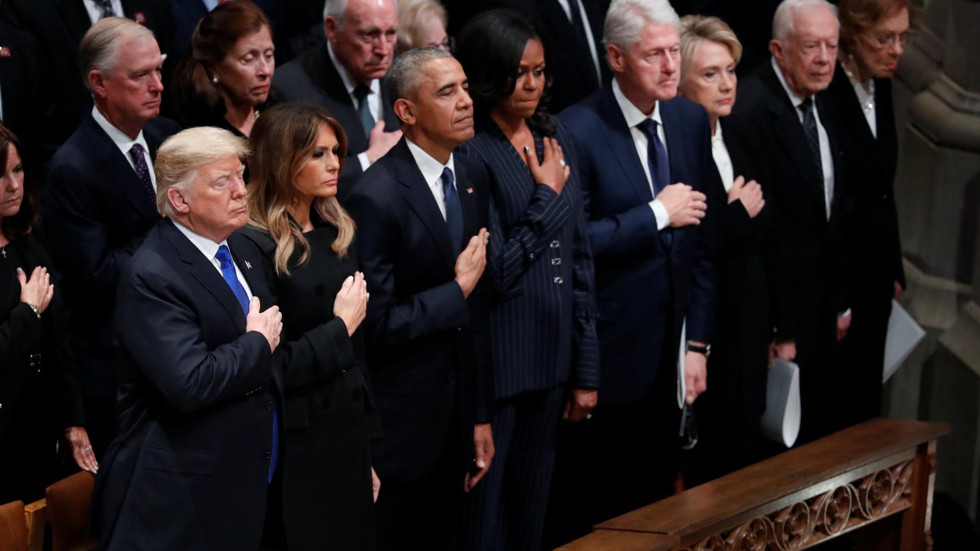 In der ersten Reihe verfolgen Präsident Donald Trump und drei ehemalige US-Präsidenten die Feier: Neben Trump und First Lady Melania Trump stehen Barack und Michelle Obama, Bill und Hillary Clinton sowie Jimmy und Rosalynn Carter.