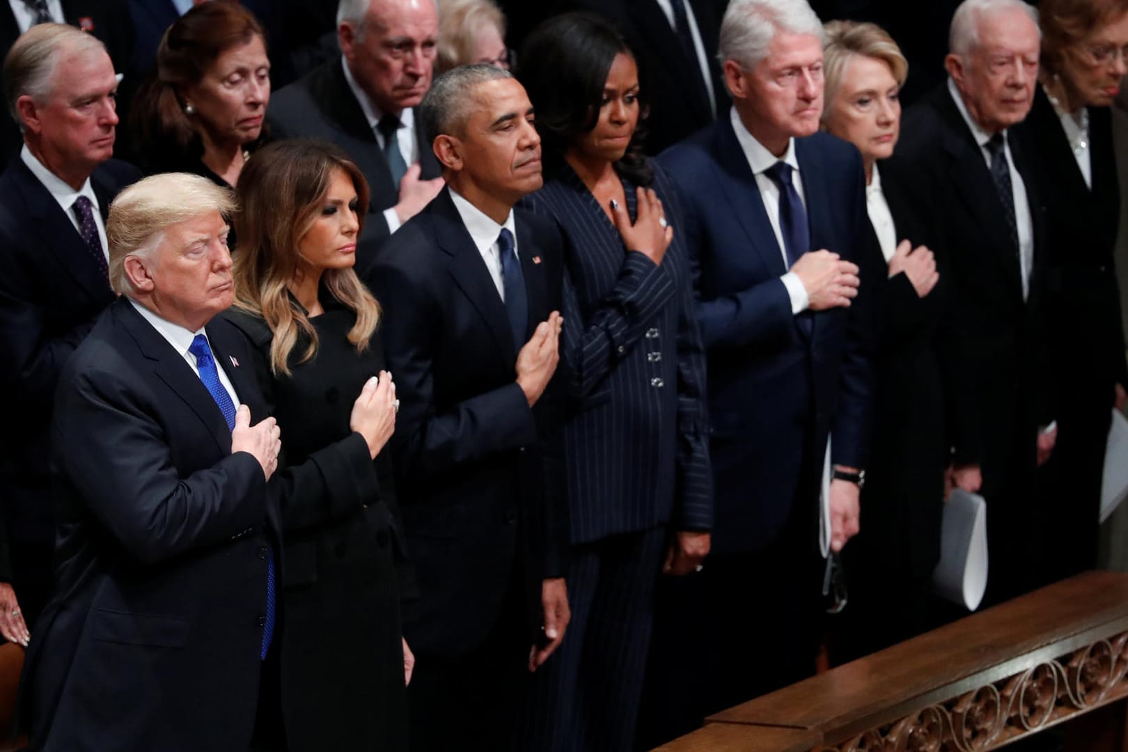 In der ersten Reihe verfolgen Präsident Donald Trump und drei ehemalige US-Präsidenten die Feier: Neben Trump und First Lady Melania Trump stehen Barack und Michelle Obama, Bill und Hillary Clinton sowie Jimmy und Rosalynn Carter.