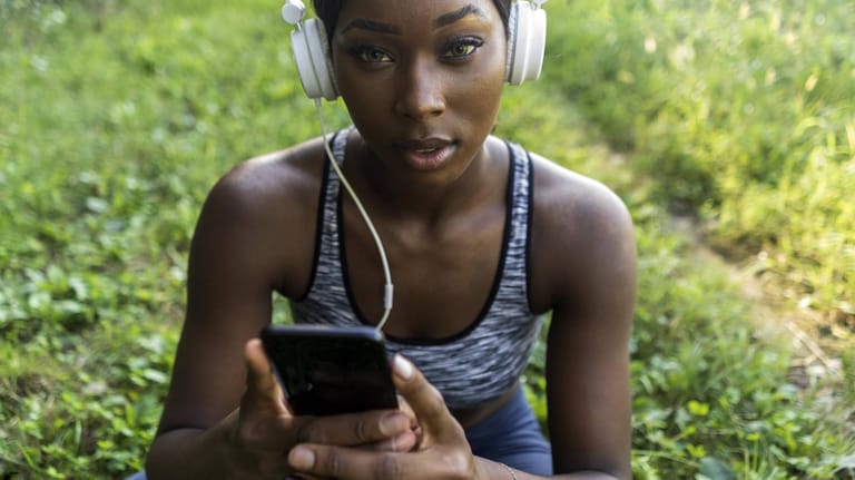 Frau mit Smartphone: Fake-Fitness-Apps buchen heimlich Geld ab