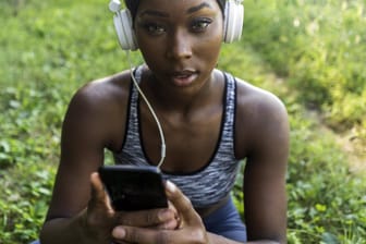 Frau mit Smartphone: Fake-Fitness-Apps buchen heimlich Geld ab
