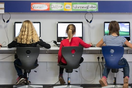 Schüler arbeiten in einem Klassenraum einer Grundschule an Computern.