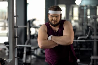 Fat man with folded hands looking at mirror, satisfied with weight loss results