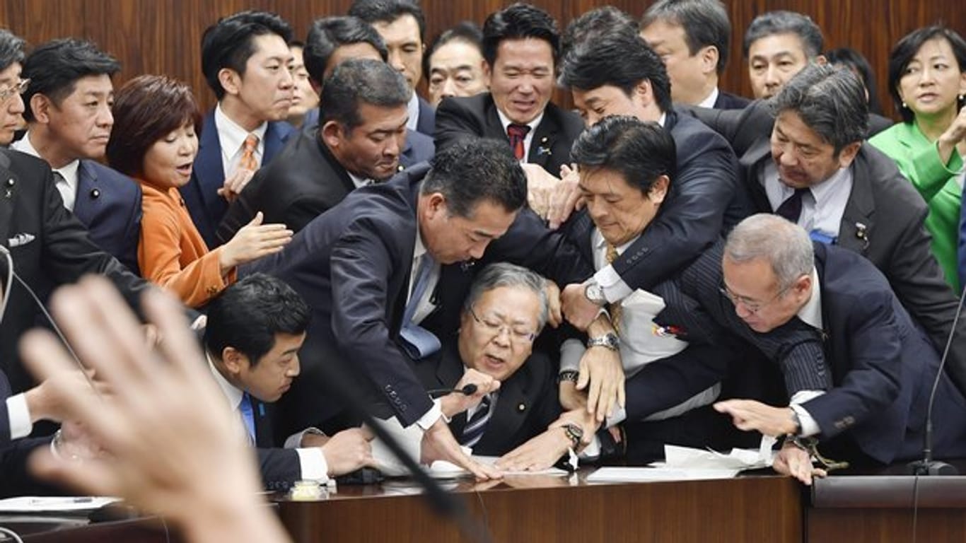 Handgemenge im japanischen Parlament: Mitglieder der Regierungspartei und der Opposition kämpfen in der Zuwanderungsdebatte um ein Mikrofon.