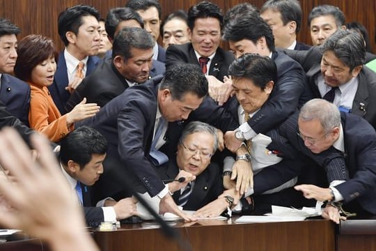 Handgemenge im japanischen Parlament: Mitglieder der Regierungspartei und der Opposition kämpfen in der Zuwanderungsdebatte um ein Mikrofon.