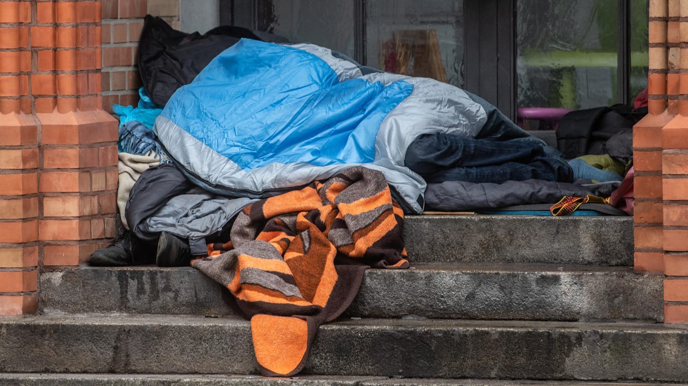 Ein Obdachloser liegt unter einer Decke in einem Eingang eines Gebäudes: Das Opfer des Angriffs blieb dank des Einschreitens der Frau unverletzt. (Symbolbild)