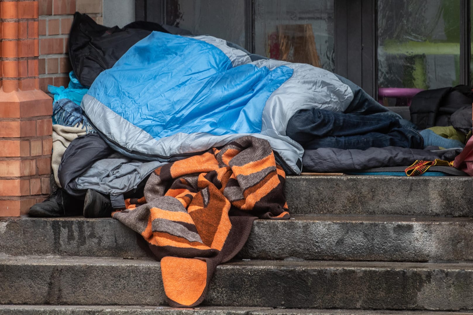Ein Obdachloser liegt unter einer Decke in einem Eingang eines Gebäudes: Das Opfer des Angriffs blieb dank des Einschreitens der Frau unverletzt. (Symbolbild)