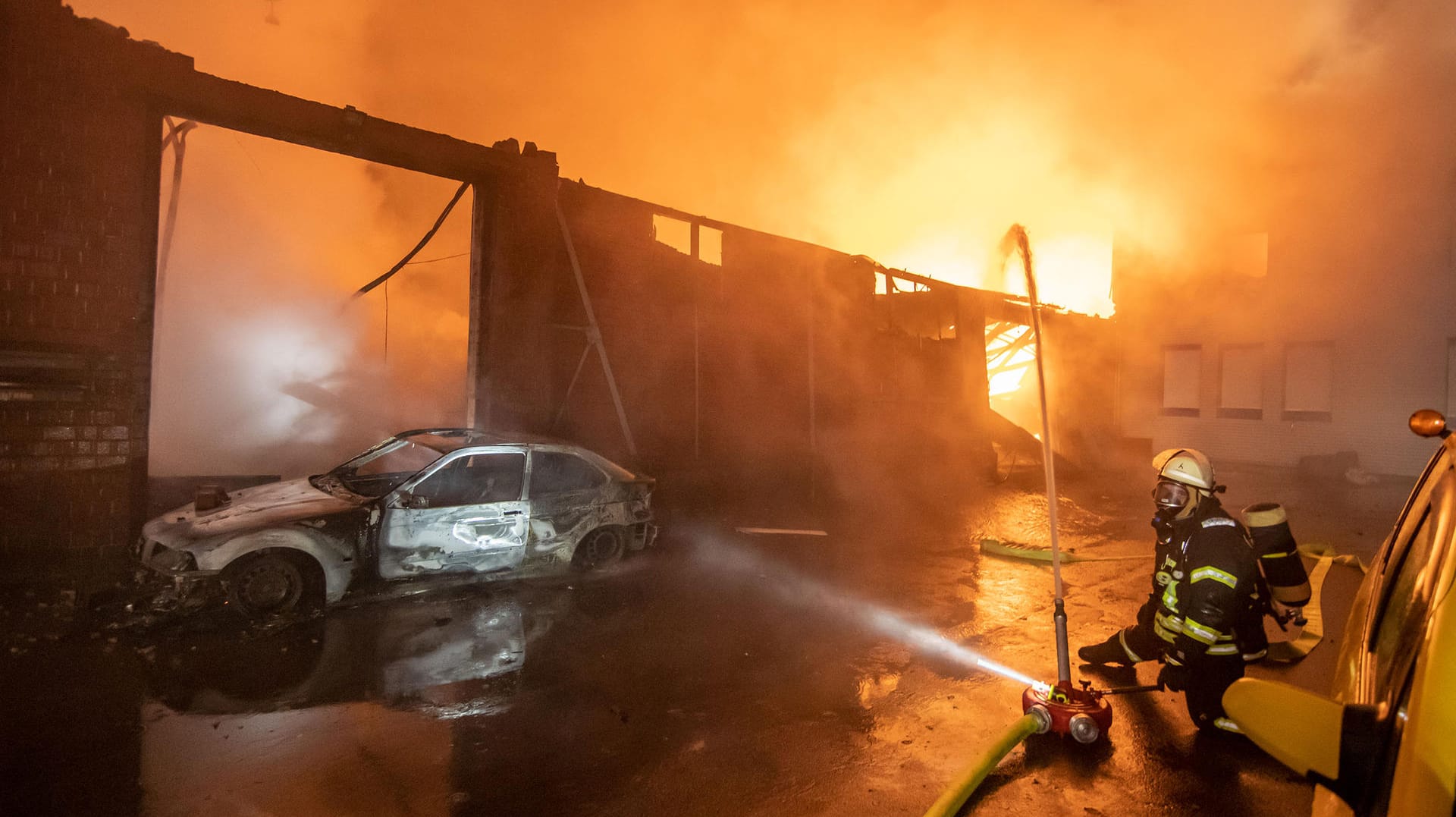 Ein Feuerwehrmann bekämpft einen Großbrand bei einem LKW-Gebrauchtwagenhändler: Insgesamt kämpften 150 Einsatzkräfte gegen die Flammen. Ein Feuerwehrmann bekämpft einen Großbrand bei einem LKW-Gebrauchtwagenhändler: Insgesamt kämpften 150 Einsatzkräfte gegen die Flammen.