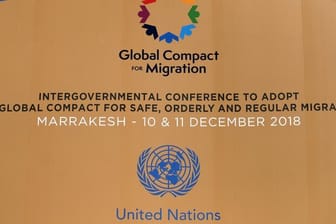 Die Logos der Vereinten Nationen und des Migrationspakts an einem Gebäude in Marrakesch.