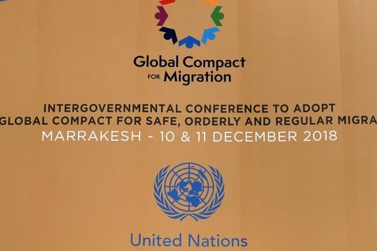 Die Logos der Vereinten Nationen und des Migrationspakts an einem Gebäude in Marrakesch.