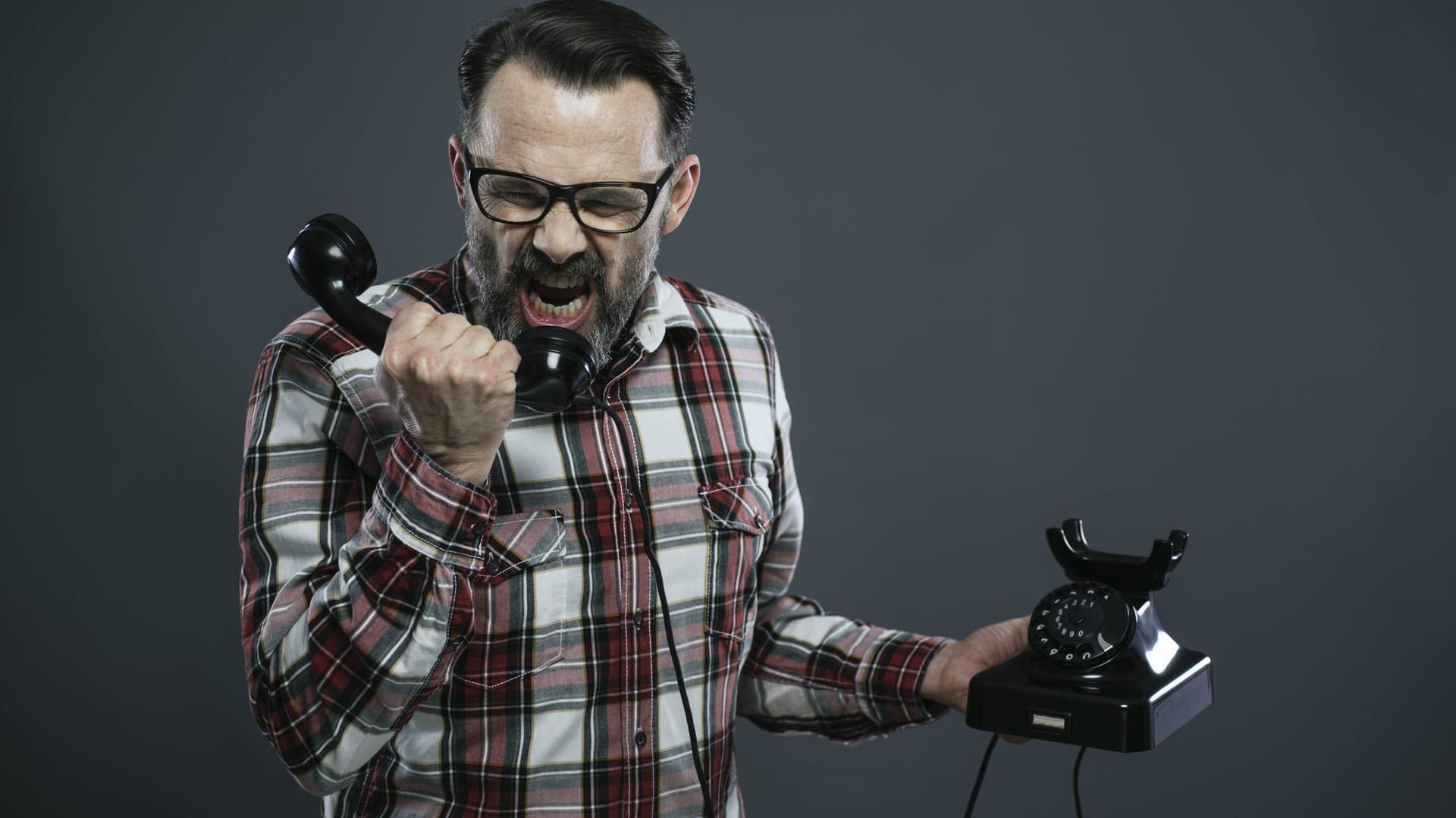 Ein Mann schreit in den Hörer eines altmodischen Telefons: Die Bundesnetzagentur hat einen Vermittler von Energieverträgen wegen "Telefonterrors" mit einem hohen Bußgeld belegt.