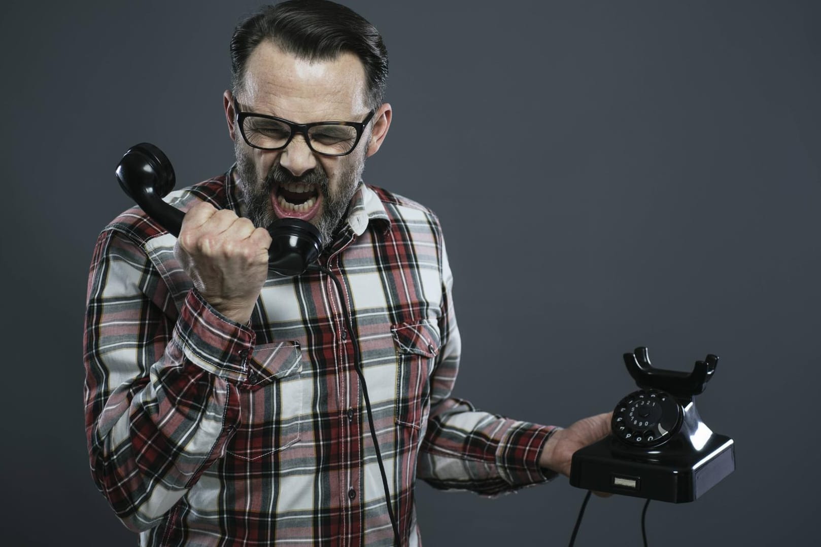Ein Mann schreit in den Hörer eines altmodischen Telefons: Die Bundesnetzagentur hat einen Vermittler von Energieverträgen wegen "Telefonterrors" mit einem hohen Bußgeld belegt.