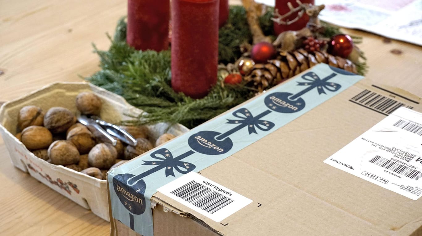 Ein Paket von Amazon liegt neben Weihnachtsdekoration: Heiligabend folgt dieses Jahr auf ein Wochenende. Online-Shopper sollten daher früh bestellen.