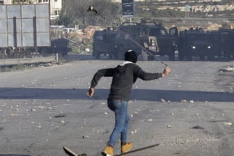 Ein Palästinenser wirft Steine auf israelische Sicherheitskräfte.
