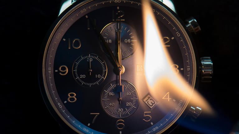 "Heißzeit": Die Flamme eines Feuerzeuges vor dem Zifferblatt einer Armbanduhr illustriert das Wort des Jahres 2018.