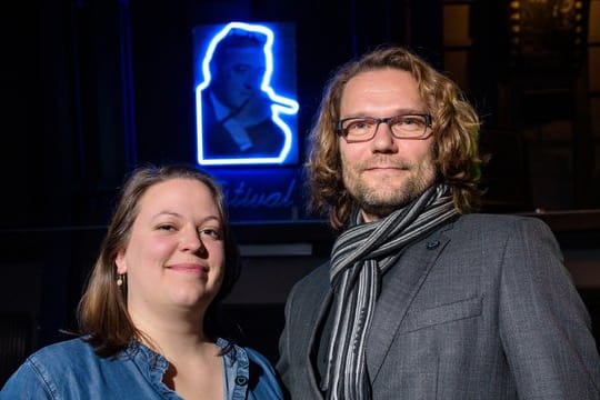 Festivalleiterin Svenja Böttger und Programmleiter Oliver Baumgarten vor einem Neon-Bild von Max Ophüls.