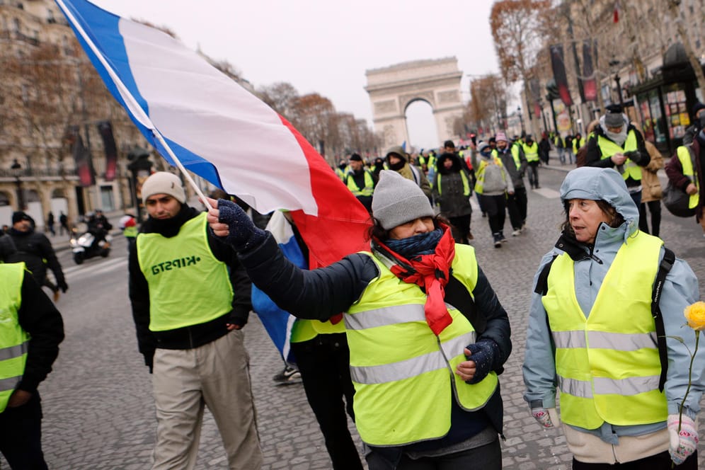 Demonstranntinnen in gelben Westen und mit französischer Fahne in Paris: Am fünften Protestwochenende in Folge ist es bislang ruhig geblieben.