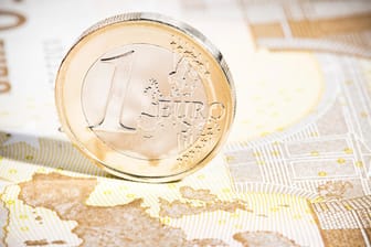 Euromünze auf Banknote: Erben können in der Regel eine Erbschaft ausschlagen. Das gilt nicht für den Staat. Doch was ist mit einem verschuldeten Erbe?
