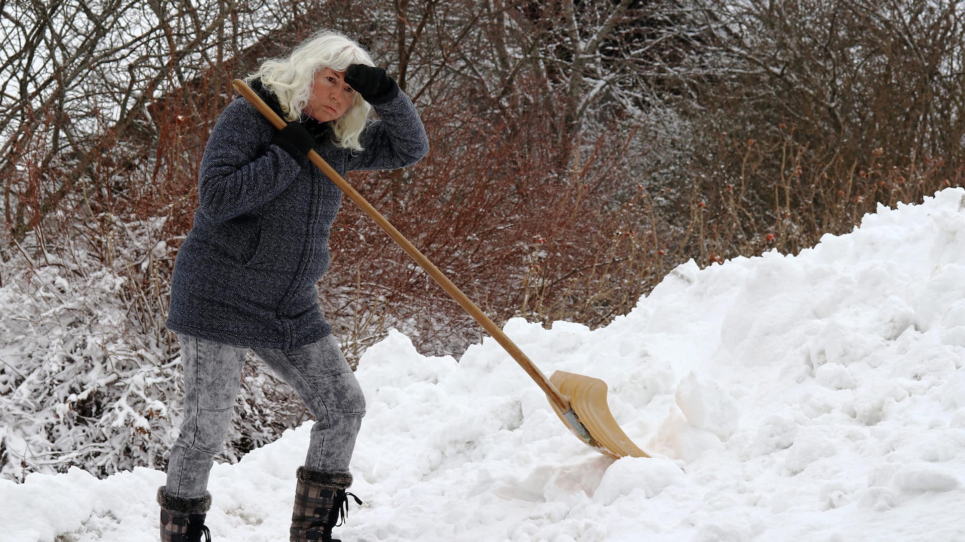 Schippe um Schippe – eine Frau schaufelt Schnee auf einen Hügel: fertig, fertiger, am fertigsten – es gibt einen Trend, Adjektive zu steigern, deren Steigerung oft Unsinn ist.