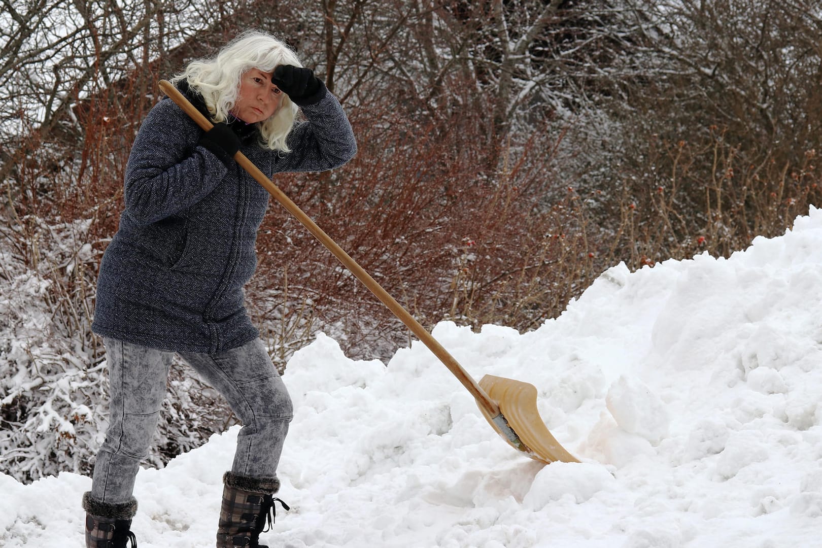 Schippe um Schippe – eine Frau schaufelt Schnee auf einen Hügel: fertig, fertiger, am fertigsten – es gibt einen Trend, Adjektive zu steigern, deren Steigerung oft Unsinn ist.