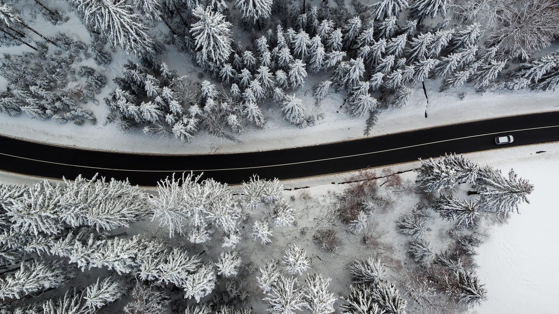 Ein Auto fährt durch den verschneiten Wald bei Geyer (Sachsen) im Erzgebirge: In Deutschland wird es an vielen Orten glatt.