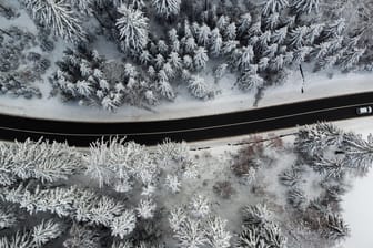 Ein Auto fährt durch den verschneiten Wald bei Geyer (Sachsen) im Erzgebirge: In Deutschland wird es an vielen Orten glatt.