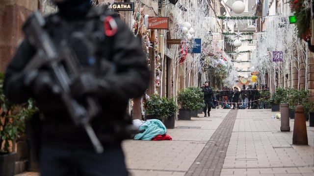 Ein Polizist steht nach einem Angriff in der Gegend des Straßburger Weihnachtsmarkts vor einem Tatort. Ein Polizist steht nach einem Angriff in der Gegend des Straßburger Weihnachtsmarkts vor einem Tatort.