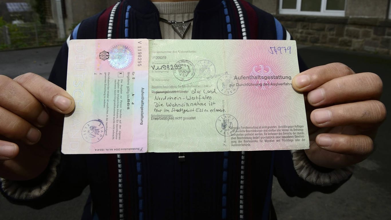 Ein syrischer Flüchtling zeigt eine Aufenthaltsgestattung: Um von deutschen Ausländerbehörden anschließend eine Aufenthaltserlaubnis erhalten zu können, kann eine Ausstellung der Verlängerung eines Passes erforderlich sein.