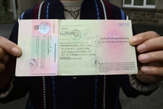 Ein syrischer Flüchtling zeigt eine Aufenthaltsgestattung: Um von deutschen Ausländerbehörden anschließend eine Aufenthaltserlaubnis erhalten zu können, kann eine Ausstellung der Verlängerung eines Passes erforderlich sein.