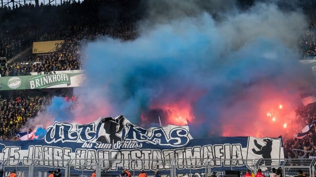 Bei Borussia Dortmund werden Feuerwerkskörper im Berliner Fanblock hinter den Bannern entzündet.