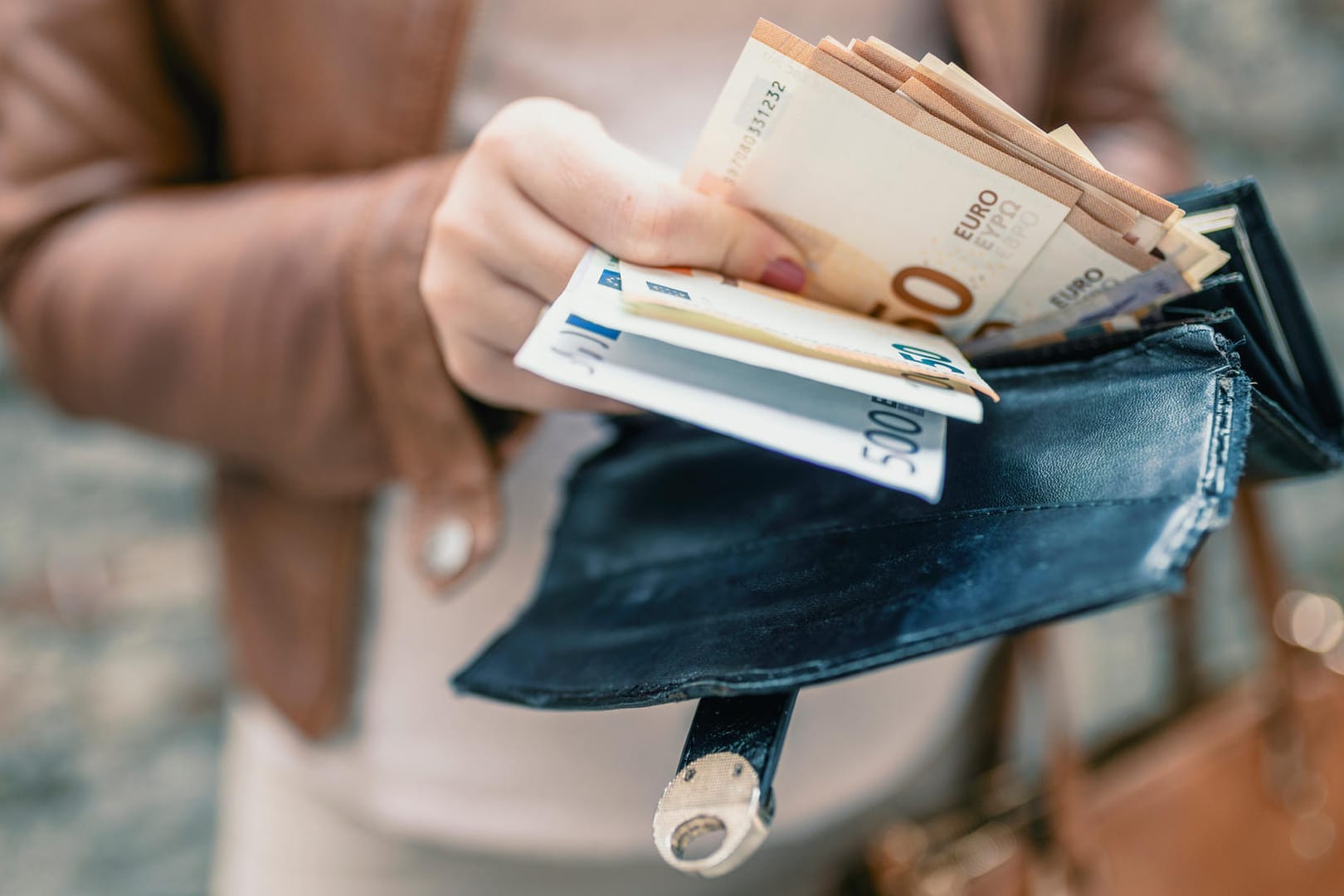 Frau steckt Euronoten in Geldbörse: Verbraucher können zum Jahreswechsel ihre steuerliche Belastung optimieren. Frau steckt Euronoten in Geldbörse: Verbraucher können zum Jahreswechsel ihre steuerliche Belastung optimieren.