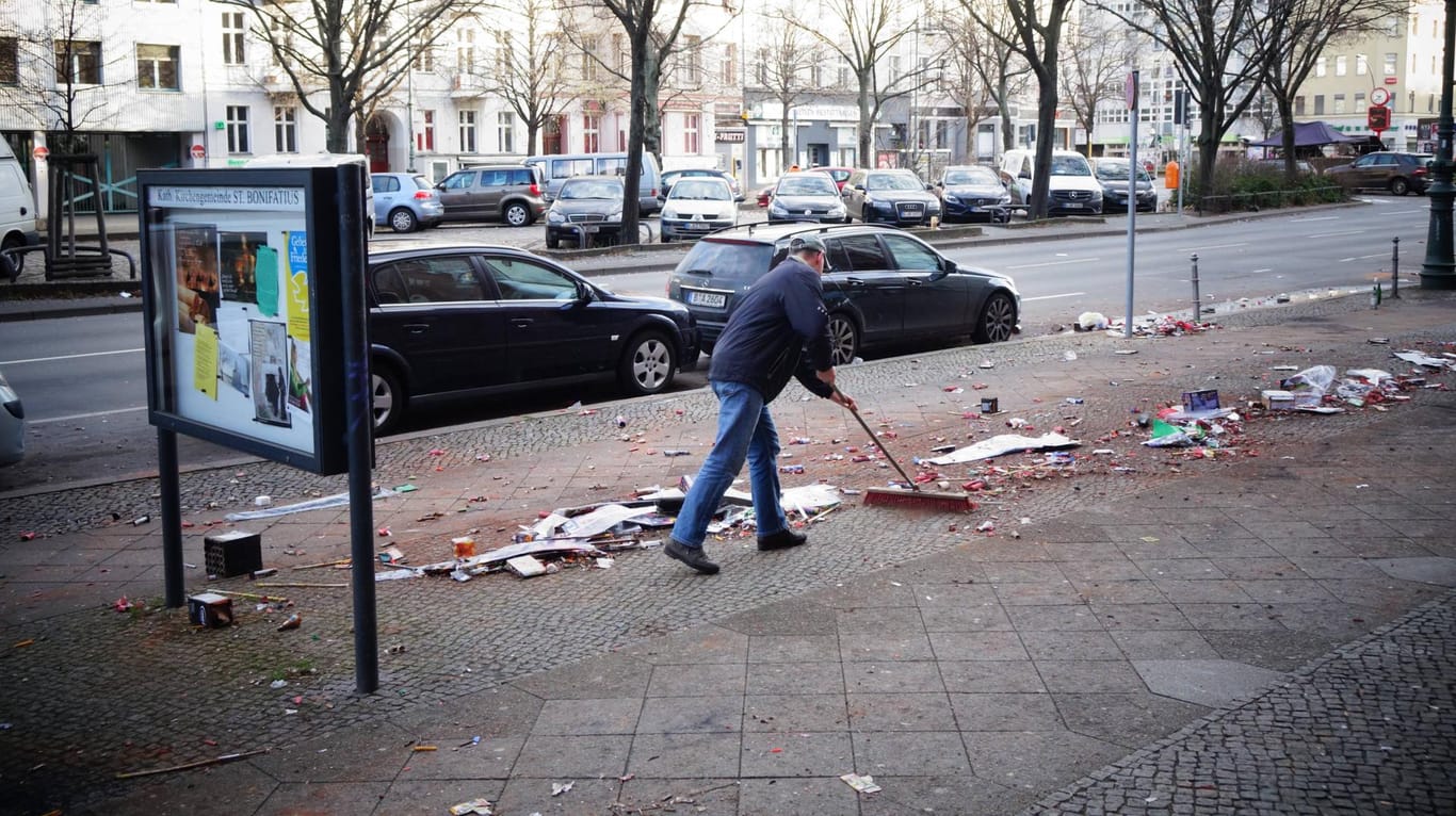 Mann reinigt Straße von Böllerabfällen: Nach der Silvesterknallerei bleibt viel Müll in den Straßen liegen.