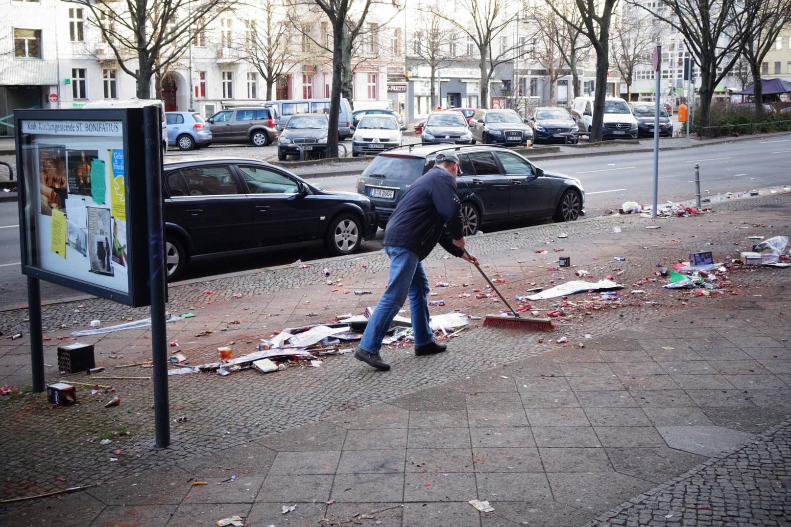 Mann reinigt Straße von Böllerabfällen: Nach der Silvesterknallerei bleibt viel Müll in den Straßen liegen.