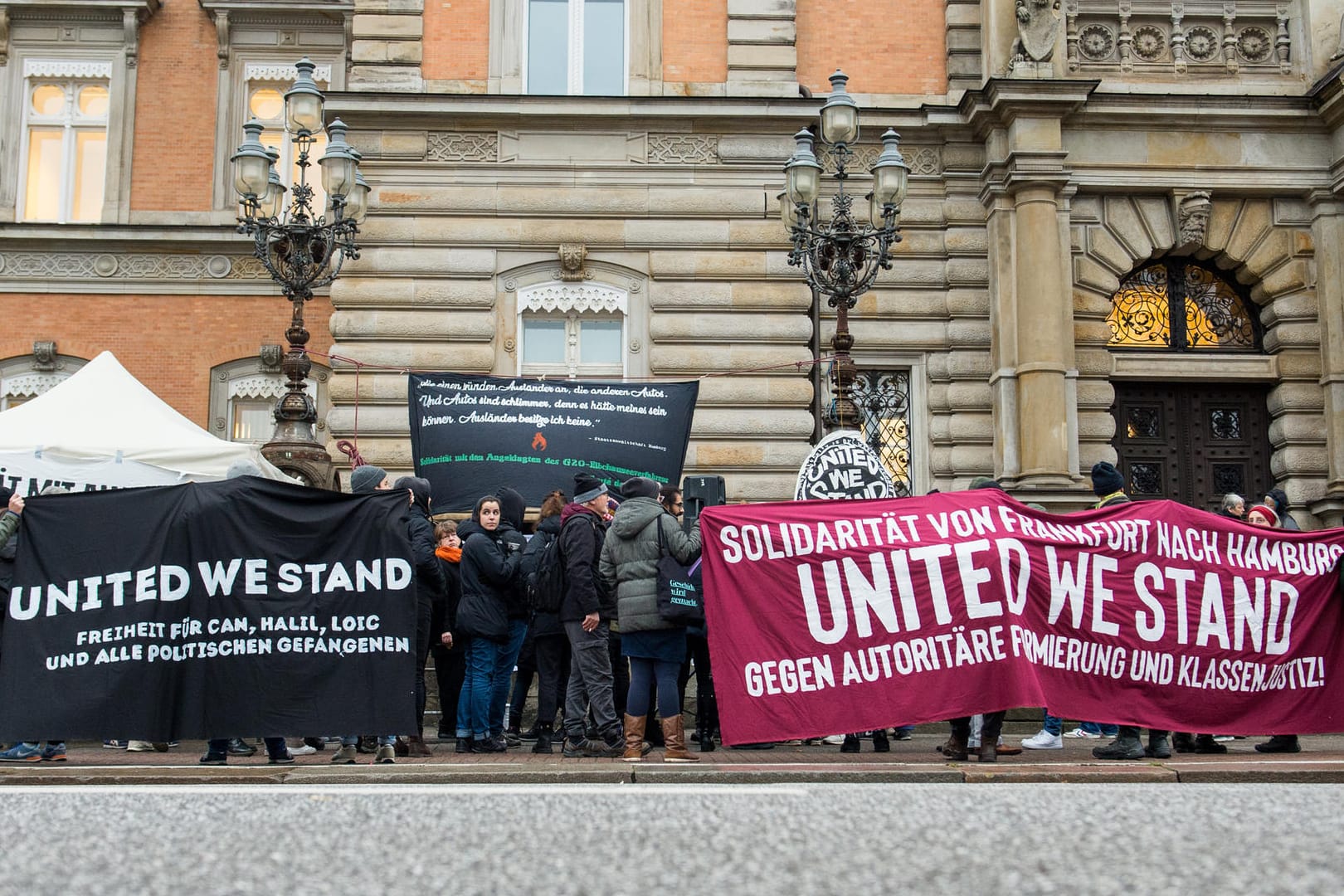 Teilnehmer einer Kundgebung halten vor dem Landgericht Transparente mit der Aufschrift "United we stand": Die Angeklagten beriefen sich auf ihr Demonstrationsrecht.