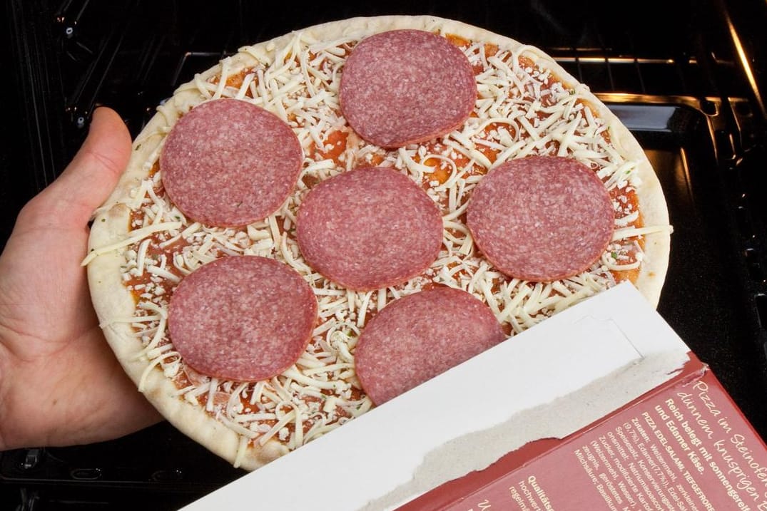 Ein Mann bereitet Tiefkühlpizza zu: Viele Fertigprodukte sollen jetzt gesünder werden.
