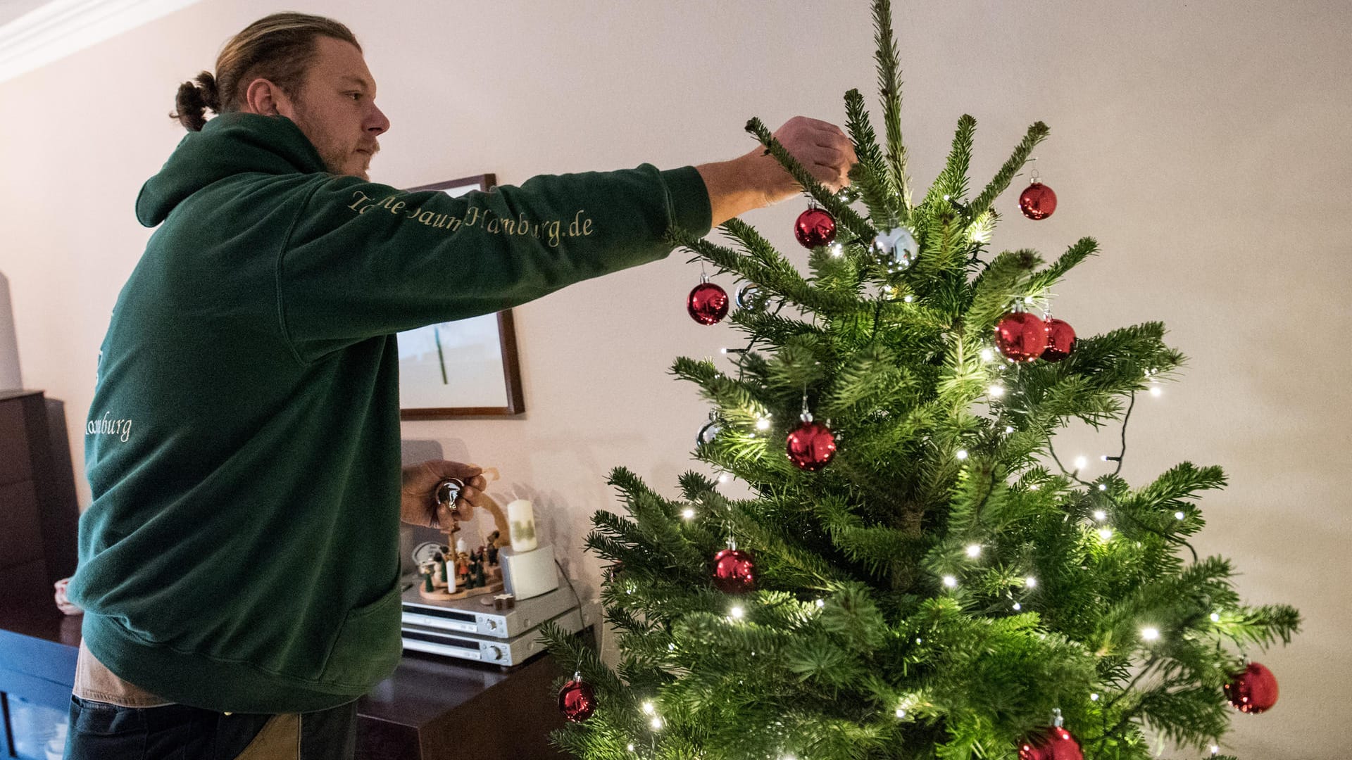 Bestellter Service: Tannenbaumhändler Gianni Kunstmann schmückt in einem Wohnzimmer eine Tanne.