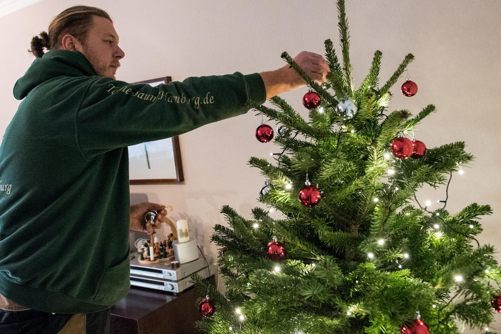 Bestellter Service: Tannenbaumhändler Gianni Kunstmann schmückt in einem Wohnzimmer eine Tanne.