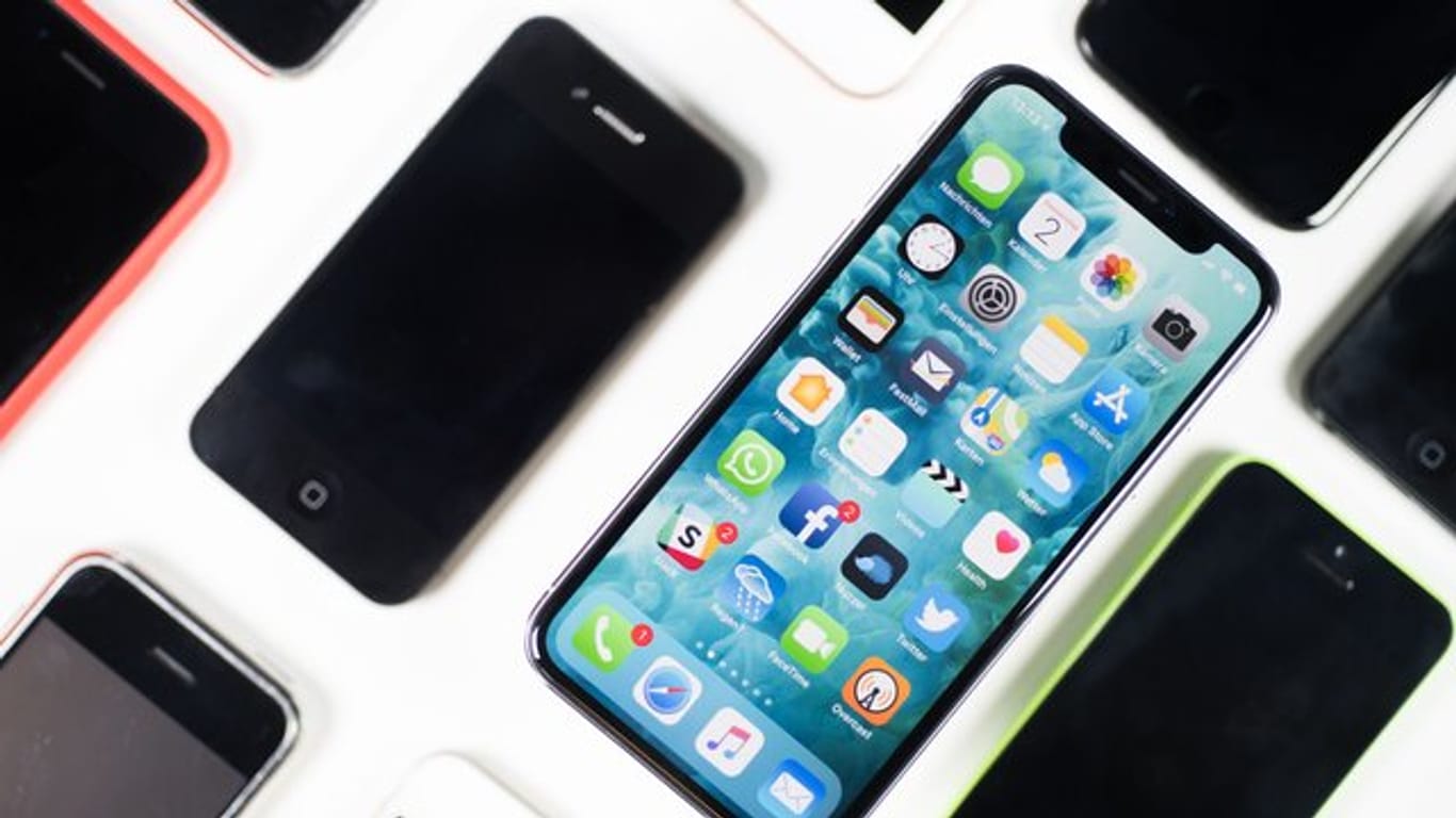 Ein iPhone X liegt neben iPhones anderer Generationen auf einem Tisch.