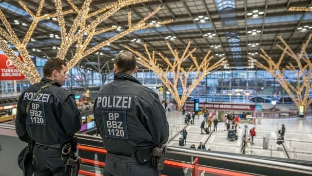 Polizisten beobachten im Flughafen Stuttgart die Check-in-Schalter.