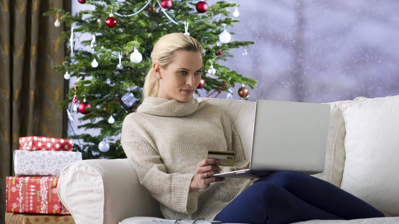 Frau mit Laptop unter Weihnachtsbaum: Notebooks sind beliebt als Geschenke