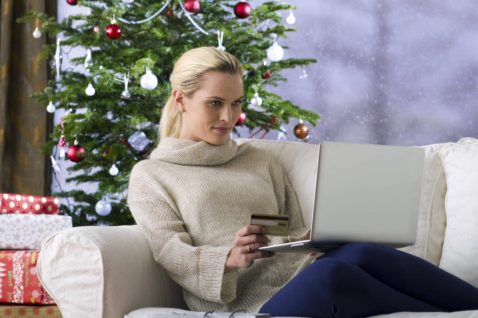 Frau mit Laptop unter Weihnachtsbaum: Notebooks sind beliebt als Geschenke