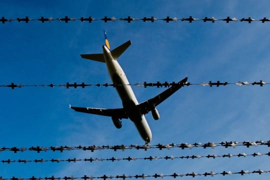 En Flugzeug fliegt am Flughafen in Hannover über Stacheldraht hinweg.